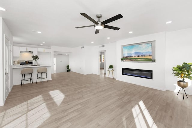 living room with visible vents, a glass covered fireplace, light wood-style flooring, ceiling fan, and recessed lighting