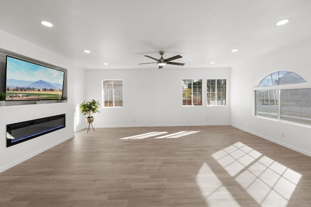 unfurnished living room featuring recessed lighting, a ceiling fan, baseboards, light wood-style floors, and a glass covered fireplace