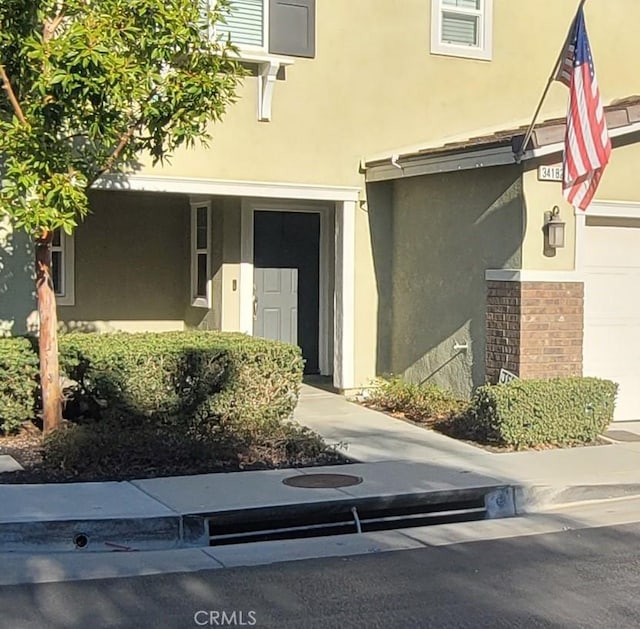 view of exterior entry featuring a garage and stucco siding