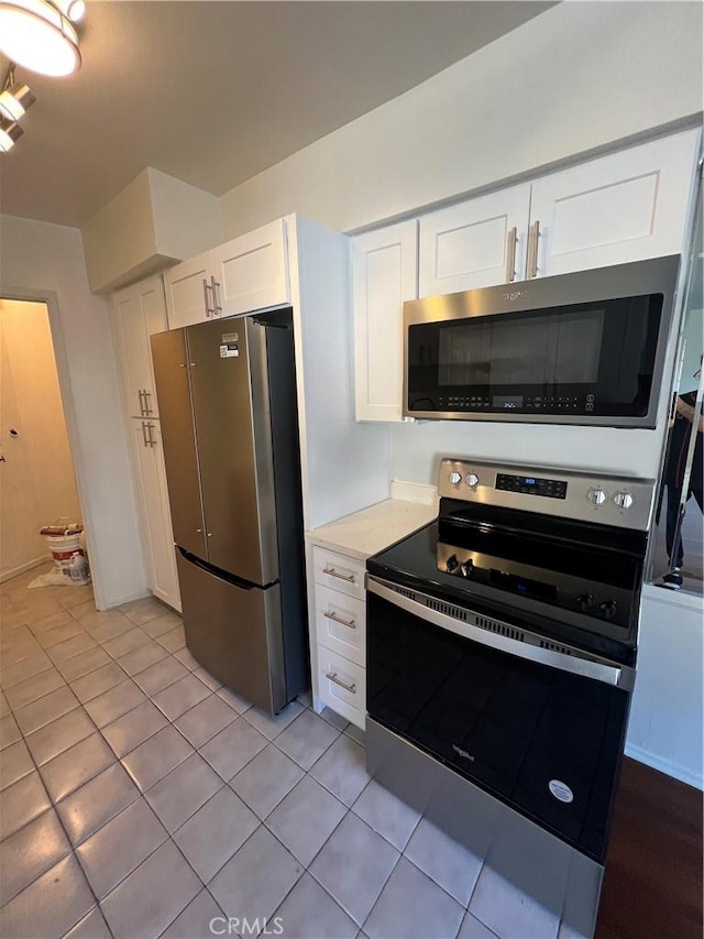 kitchen with white cabinets, light tile patterned floors, stainless steel appliances, and light countertops