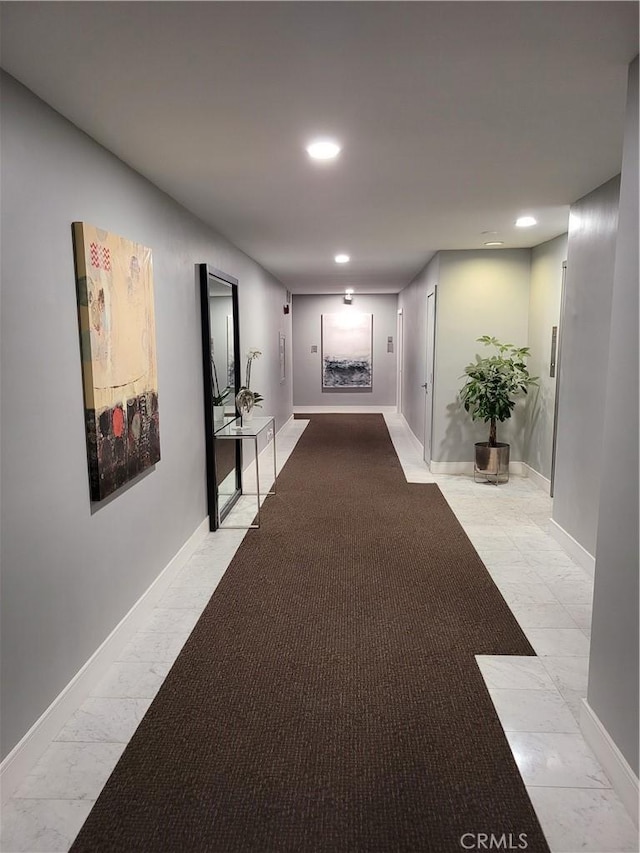 hallway featuring marble finish floor, baseboards, and recessed lighting