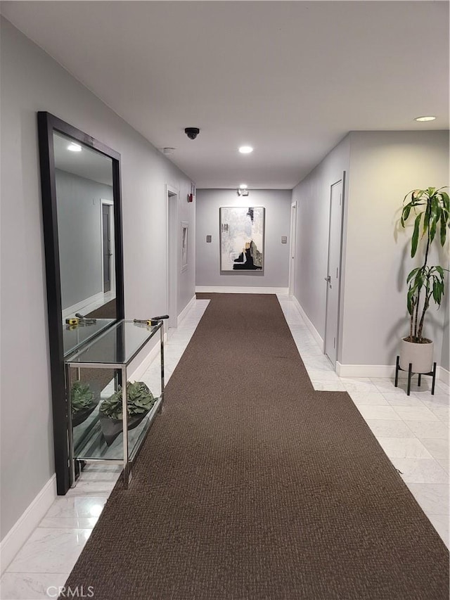 corridor featuring marble finish floor and baseboards