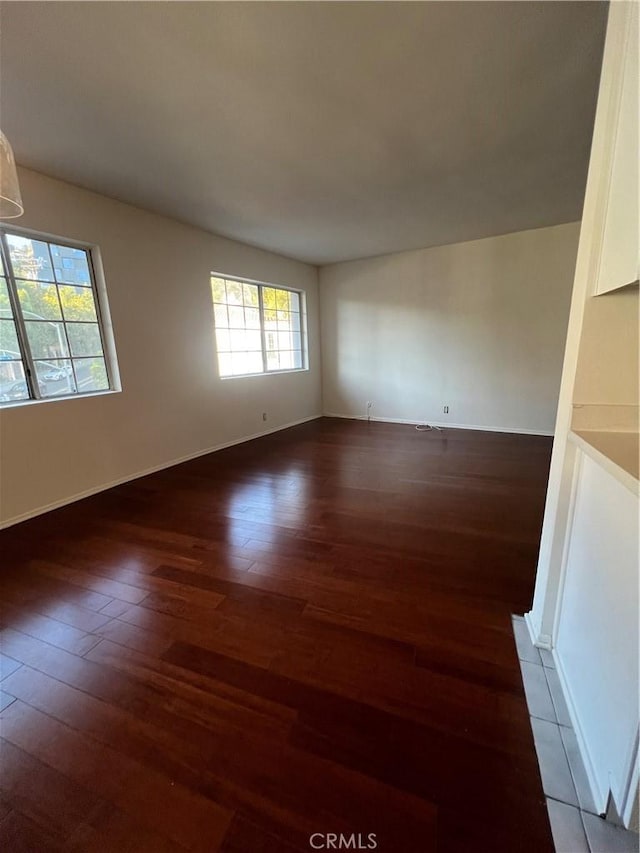 spare room featuring baseboards and wood finished floors