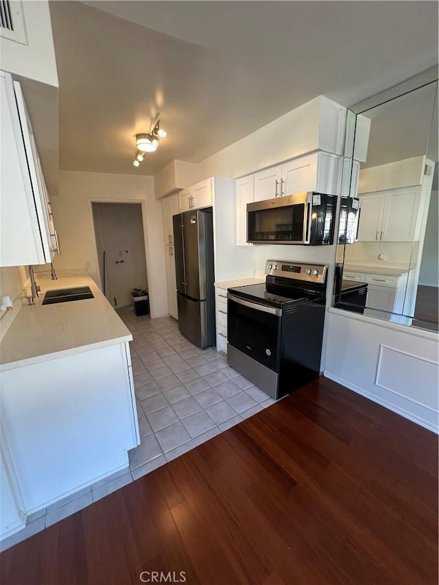 kitchen with white cabinets, light wood finished floors, stainless steel appliances, and a sink