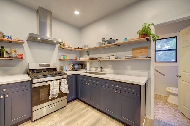 kitchen featuring appliances with stainless steel finishes, a sink, wall chimney range hood, and open shelves