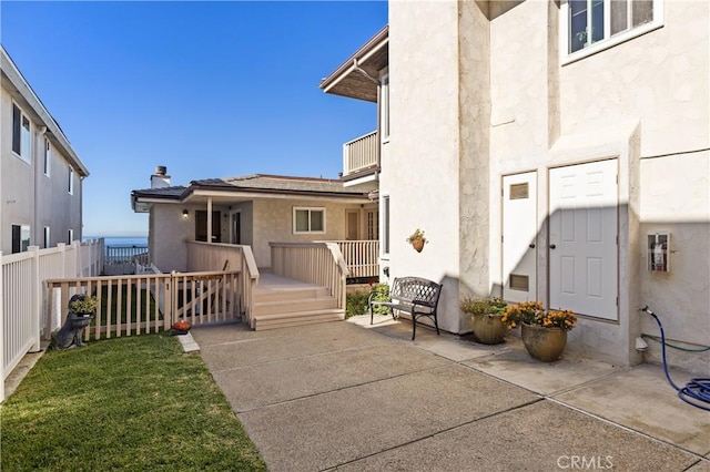 back of house featuring a deck, fence, a lawn, stucco siding, and a patio area