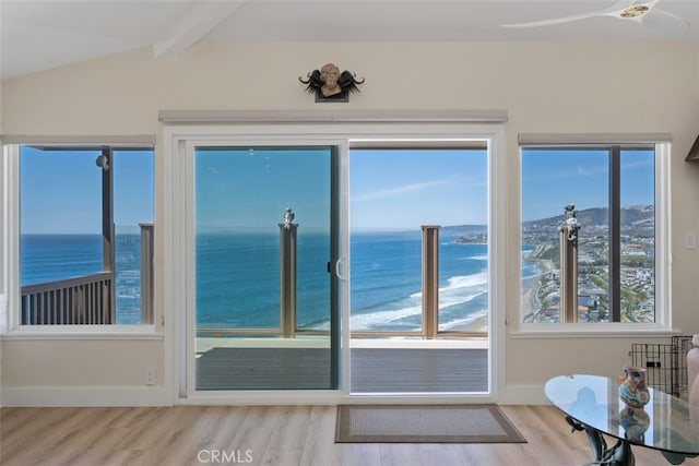 doorway featuring lofted ceiling with beams, wood finished floors, baseboards, a water view, and ceiling fan