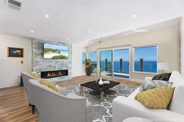 living area featuring visible vents, a high end fireplace, wood finished floors, recessed lighting, and lofted ceiling