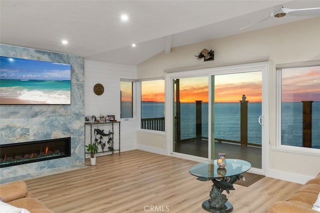 living area with a water view, lofted ceiling, wood finished floors, and recessed lighting