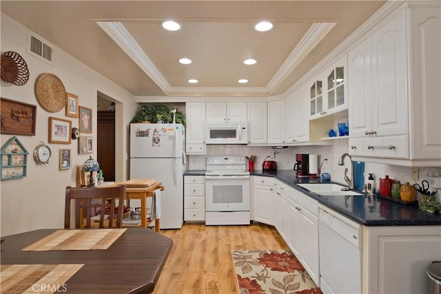 kitchen featuring white appliances, a sink, visible vents, a tray ceiling, and dark countertops