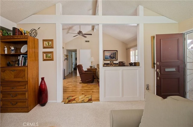 carpeted foyer featuring lofted ceiling, visible vents, a textured ceiling, and a ceiling fan