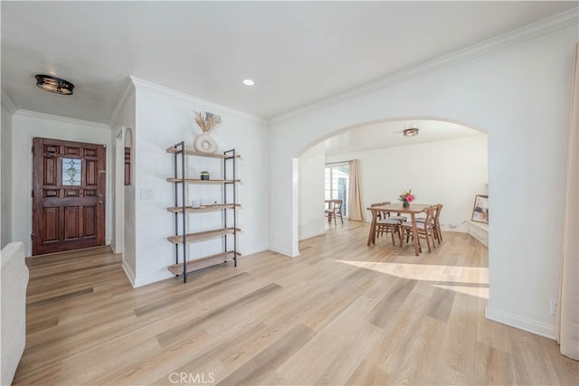 entrance foyer with crown molding, light wood-style floors, arched walkways, and baseboards