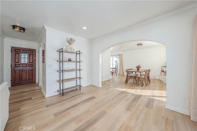 foyer featuring light wood-type flooring, baseboards, ornamental molding, and arched walkways
