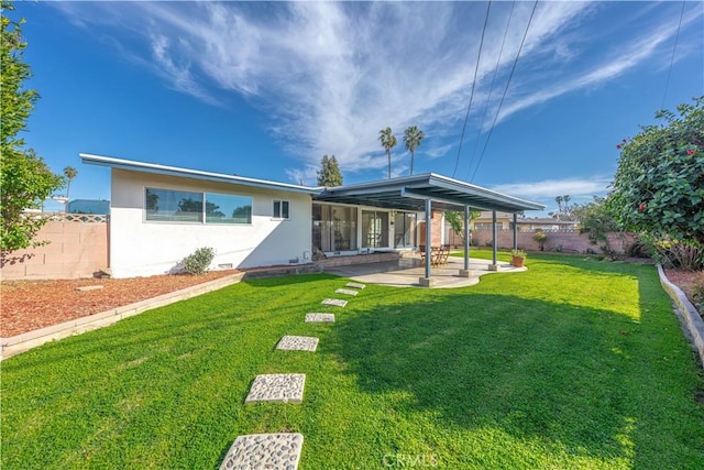 rear view of house featuring a lawn, a patio, stucco siding, and a fenced backyard