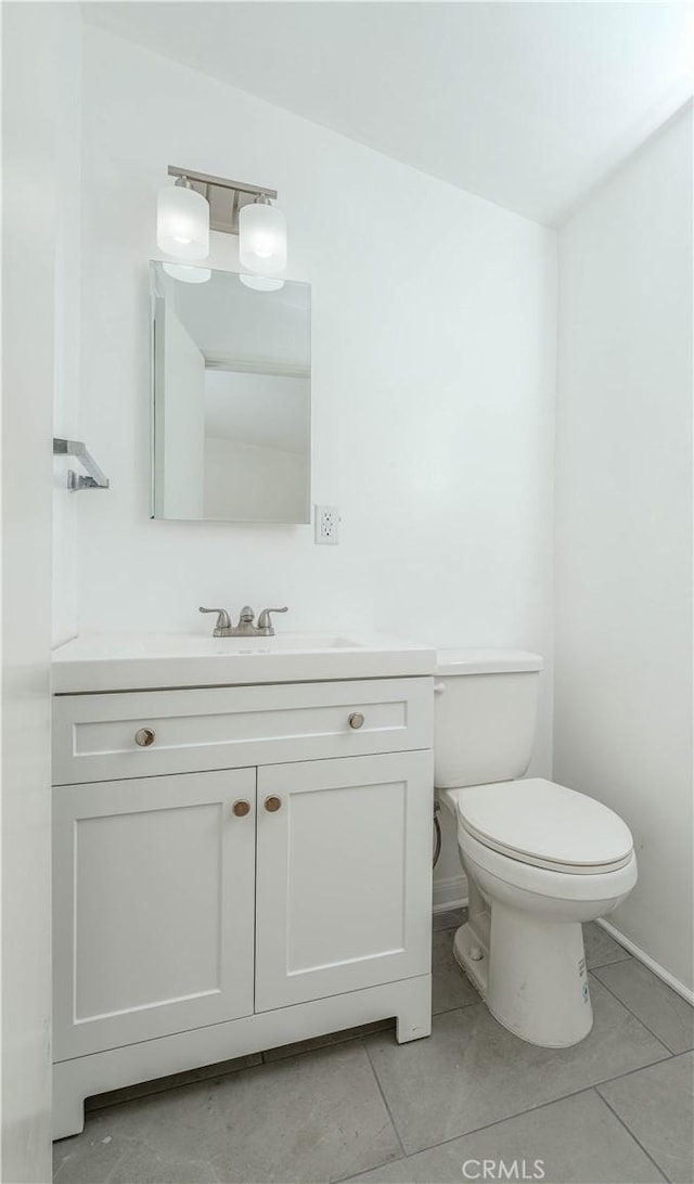 half bath with tile patterned floors, toilet, and vanity