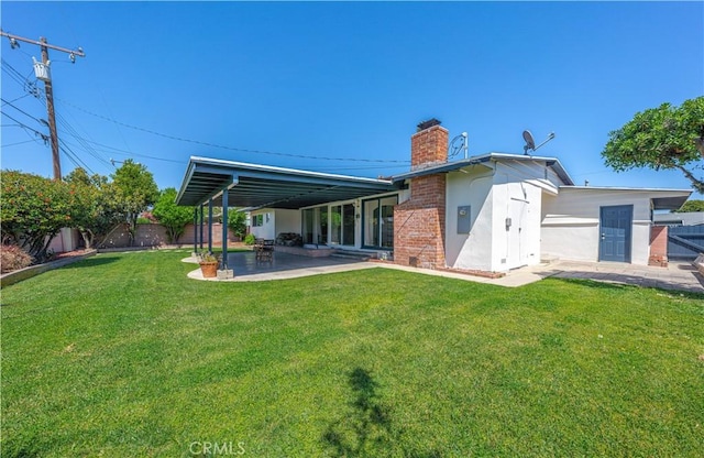back of property featuring a chimney, a fenced backyard, a lawn, and a patio area