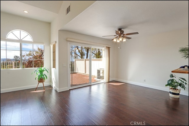 empty room with visible vents, ceiling fan, dark wood-type flooring, and baseboards