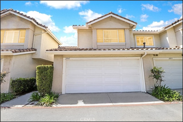 view of property with concrete driveway, a tile roof, and stucco siding