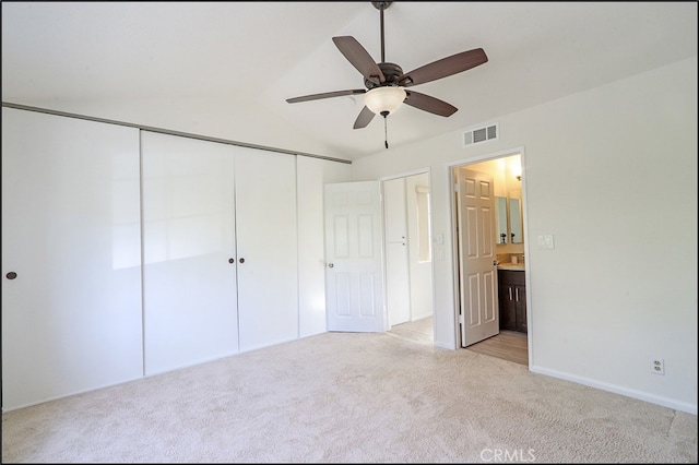 unfurnished bedroom with visible vents, ensuite bath, a closet, light colored carpet, and vaulted ceiling