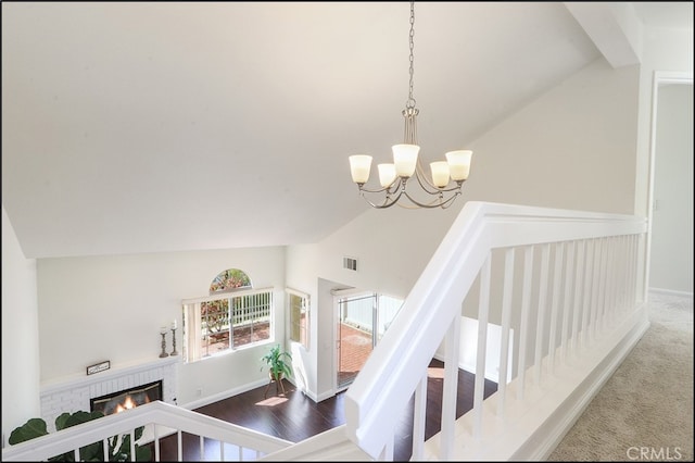 staircase with visible vents, baseboards, a notable chandelier, and a brick fireplace