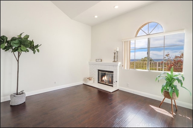 living room featuring baseboards, a brick fireplace, and wood finished floors