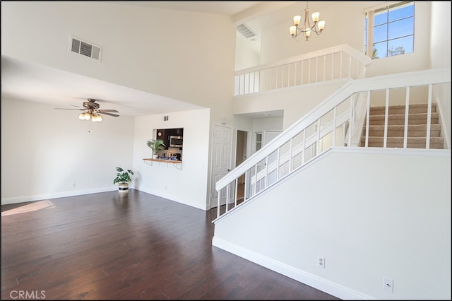 interior space featuring visible vents, high vaulted ceiling, ceiling fan with notable chandelier, wood finished floors, and baseboards