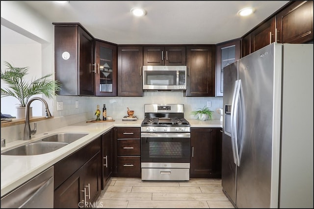 kitchen with a sink, light countertops, dark brown cabinets, appliances with stainless steel finishes, and backsplash