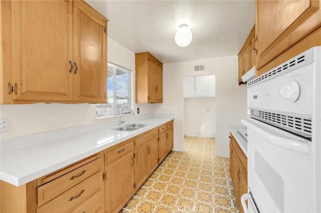 kitchen with visible vents, light countertops, a sink, and white oven