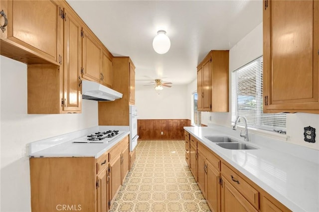 kitchen featuring under cabinet range hood, white gas stovetop, a sink, a ceiling fan, and light countertops