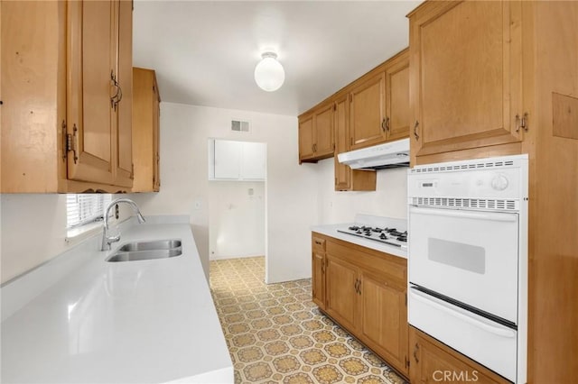 kitchen featuring white gas stovetop, visible vents, light countertops, under cabinet range hood, and a sink