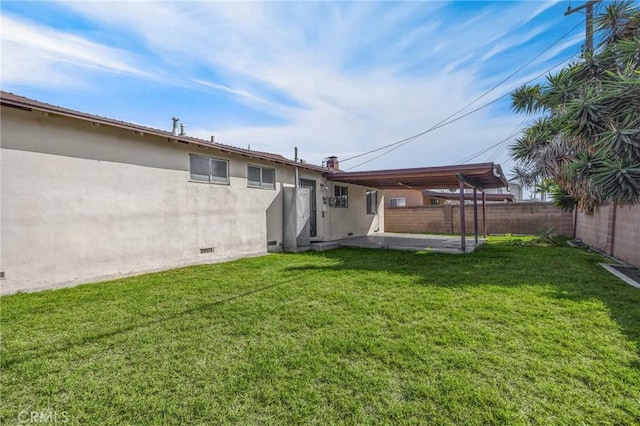 rear view of property featuring a lawn, crawl space, fence, a patio area, and stucco siding