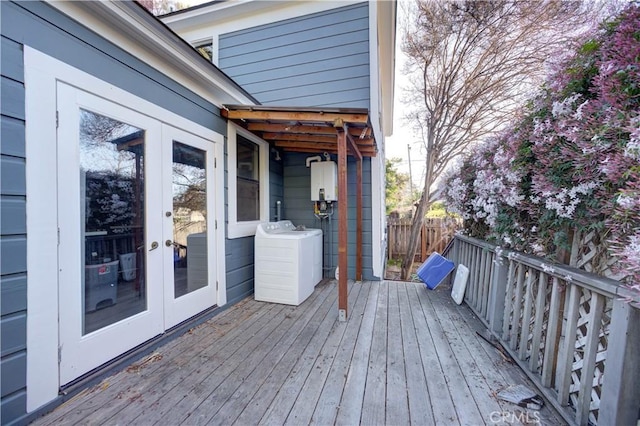 wooden terrace featuring water heater, washer / clothes dryer, fence, and french doors