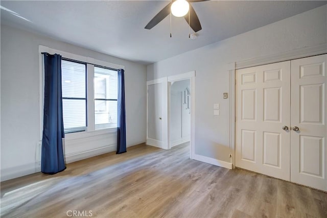 unfurnished bedroom with light wood finished floors, ceiling fan, baseboards, and a closet