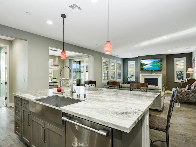 kitchen featuring a fireplace, wood finished floors, a sink, visible vents, and stainless steel dishwasher