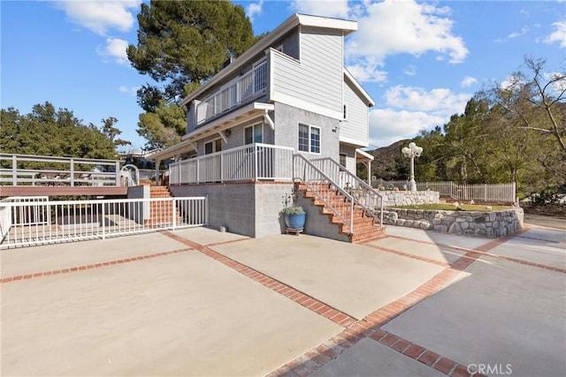 exterior space featuring driveway, stairs, and fence