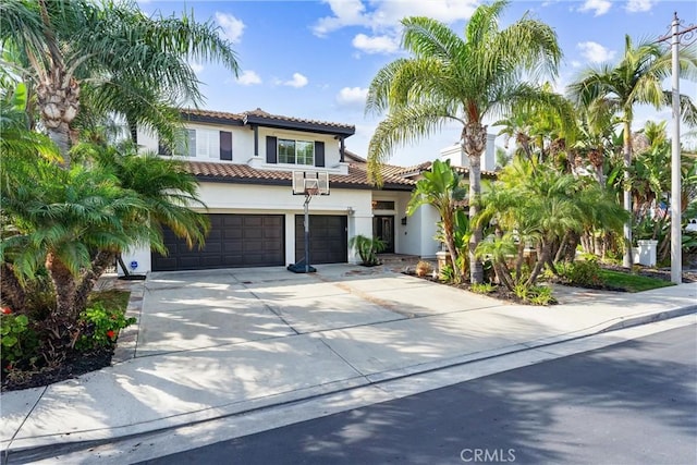 mediterranean / spanish house with a tile roof, driveway, and stucco siding