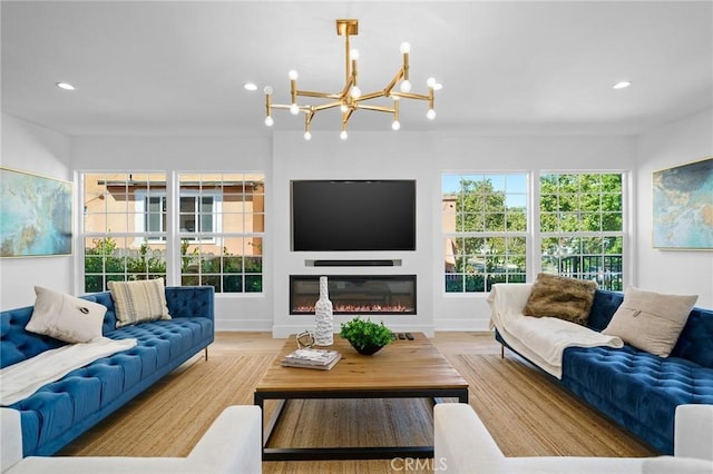 living room featuring a glass covered fireplace, wood finished floors, baseboards, and recessed lighting