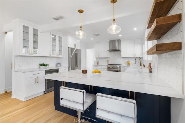 kitchen with beverage cooler, a peninsula, high quality appliances, wall chimney range hood, and open shelves