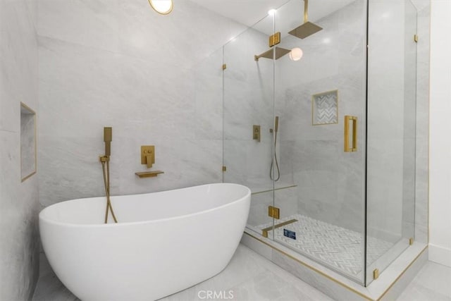 bathroom featuring a soaking tub, a shower stall, marble finish floor, and tile walls