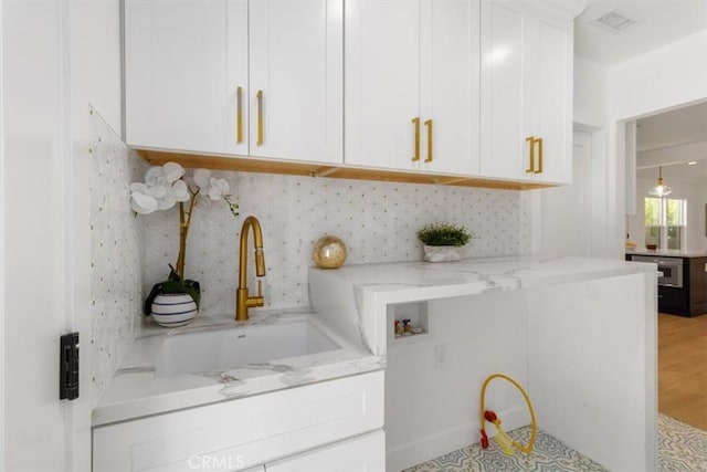 washroom featuring washer hookup, visible vents, cabinet space, light wood-style floors, and a sink