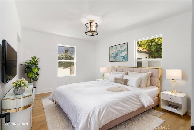 bedroom featuring light wood-style floors and an inviting chandelier