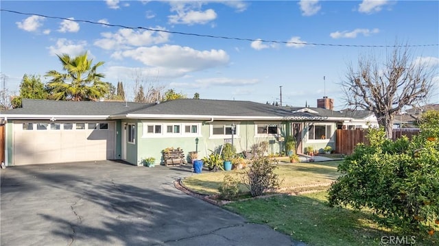 ranch-style home with a garage, driveway, and fence