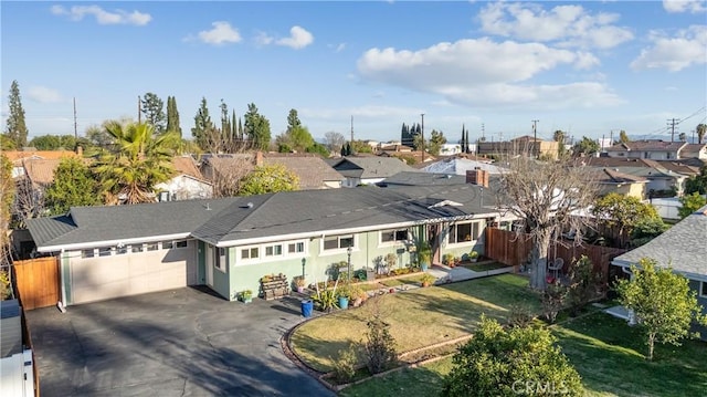 ranch-style house with an attached garage, fence, driveway, a residential view, and a front yard