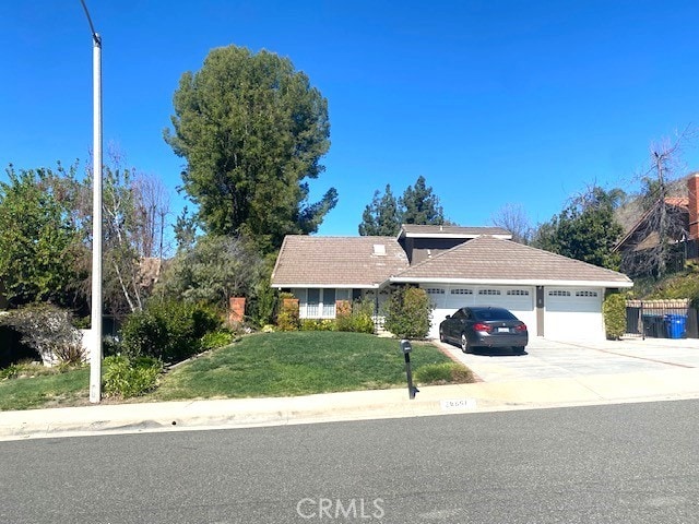 view of front of property featuring a garage, concrete driveway, and a front lawn