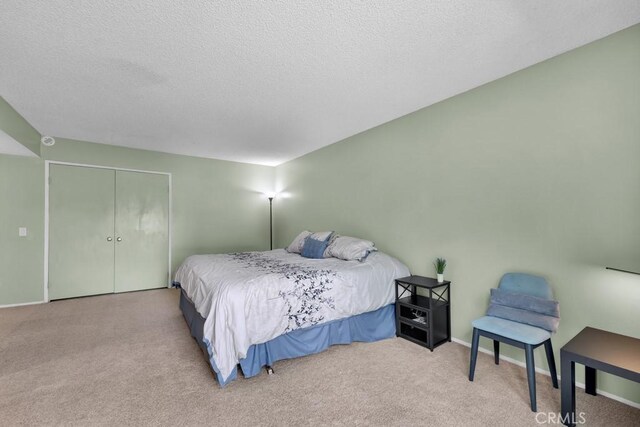carpeted bedroom featuring a textured ceiling, baseboards, and a closet