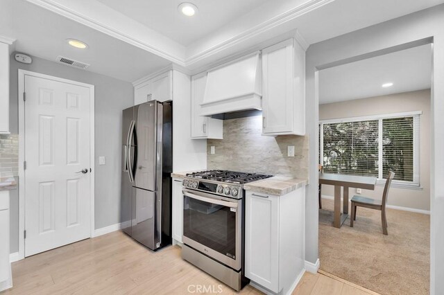 kitchen featuring white cabinets, stainless steel appliances, visible vents, and custom exhaust hood