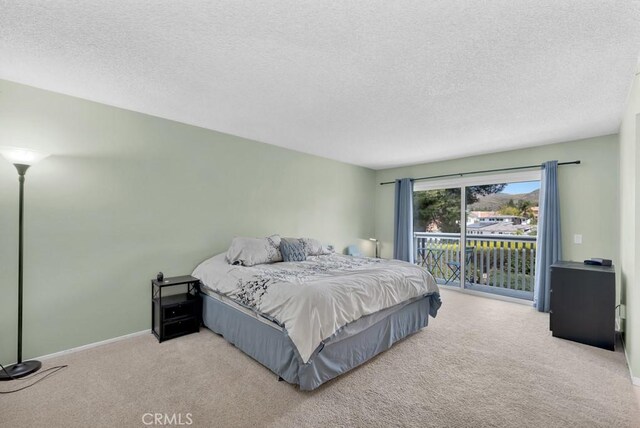 carpeted bedroom with access to outside, a textured ceiling, and baseboards