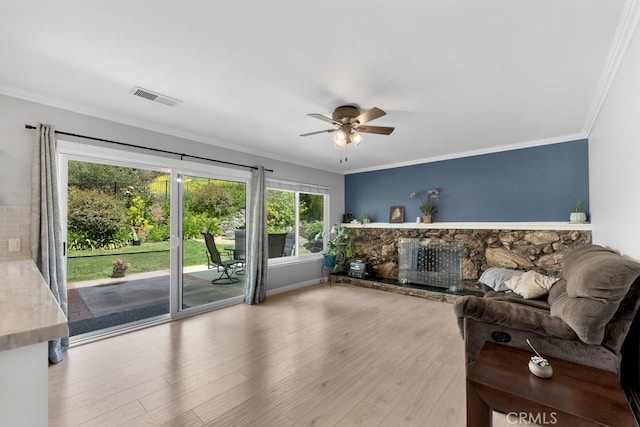 living room with crown molding, ceiling fan, wood finished floors, and visible vents