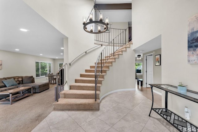 stairway with tile patterned floors, a notable chandelier, recessed lighting, and a towering ceiling