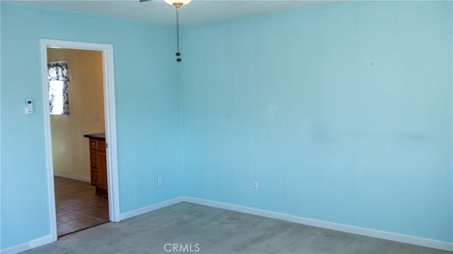 spare room featuring light colored carpet and baseboards